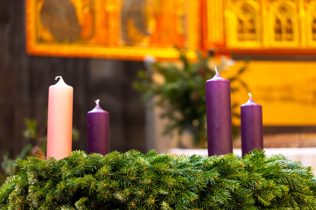 advent wreath in a church with violet and pink candles